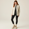 Frau mit langen roten Haaren trägt eine beige Jacke, graues Oberteil, schwarze Leggings und beige Stiefeletten