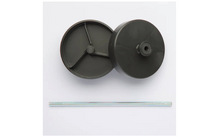 Zwei schwarze Kunststoffscheiben, eine mit drei innenliegenden Speichen sichtbar, die andere mit zentralem Zapfen; darunter eine lange dünne Metallstange auf weißem Hintergrund