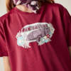 Bordeauxrotes T‑Shirt mit Aufdruck eines Kleinbusses und Blumen, gemustertes Halstuch am Hals