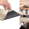 Hand holding a rectangular beige material; a corner is lifted to show a black underside with repeated white lettering; top right a piece lies in a cabinet next to several cups; bottom right a hand cuts the material with scissors
