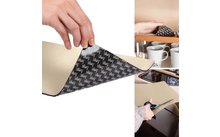 Hand holding a rectangular beige material; a corner is lifted to show a black underside with repeated white lettering; top right a piece lies in a cabinet next to several cups; bottom right a hand cuts the material with scissors