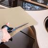 Hand cutting a beige mat with scissors over a sink