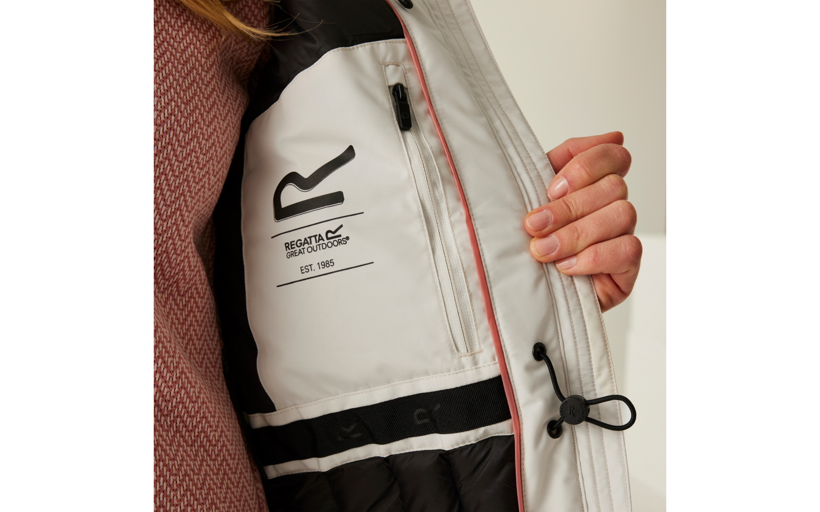 Hand hält die Innenseite einer Jacke mit einem eingenähten Etikett