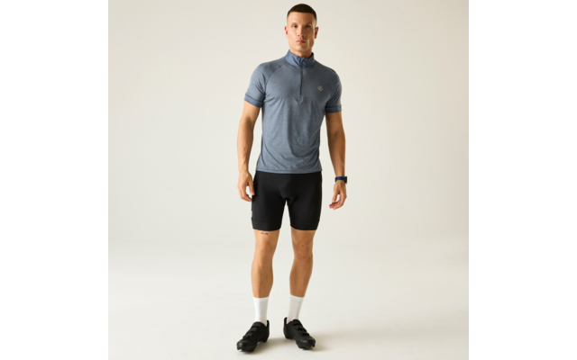 Mann in blauem, kurzärmeligem Fahrradtrikot mit Reißverschluss, schwarzer Radhose, weißen Socken und schwarzen Fahrradschuhen, steht frontal vor hellem Hintergrund