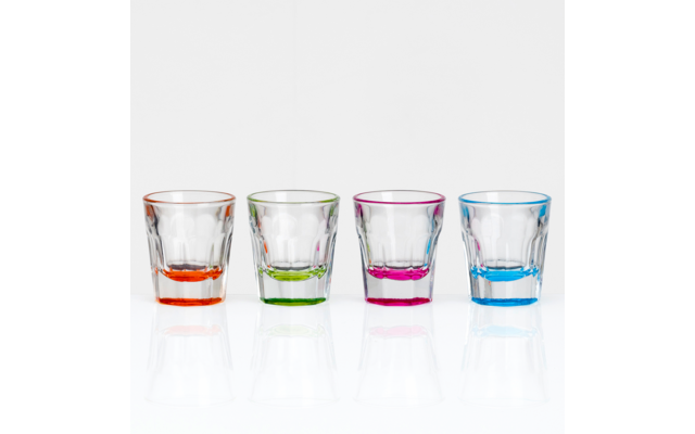 Four clear shot glasses with colored bases (orange, green, pink, blue) lined up on a white background with reflections
