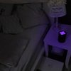 Nachttisch mit Lampe und Wecker neben einem Bett