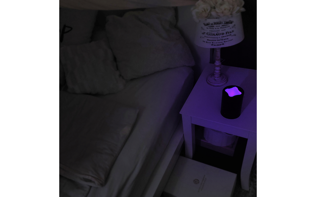 Nachttisch mit Lampe und Wecker neben einem Bett