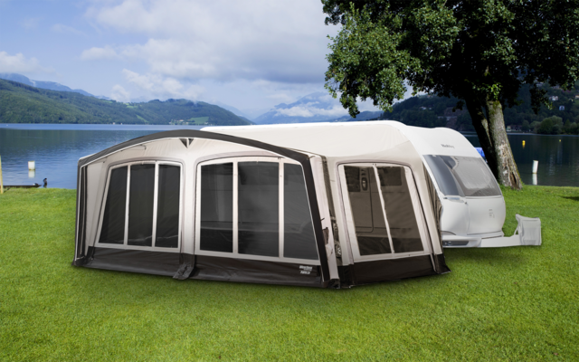 Weißer Wohnwagen mit grauem Vorzelt und mehreren großen Fenstern