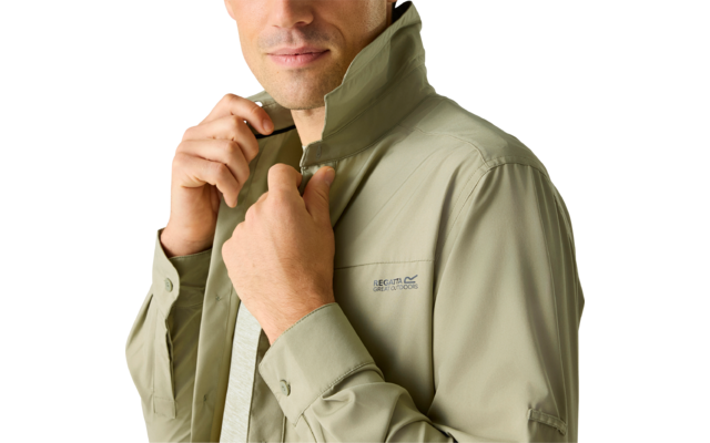 Mann in olivgrüner Jacke, hält den hohen Kragen mit beiden Händen und schaut nach unten rechts