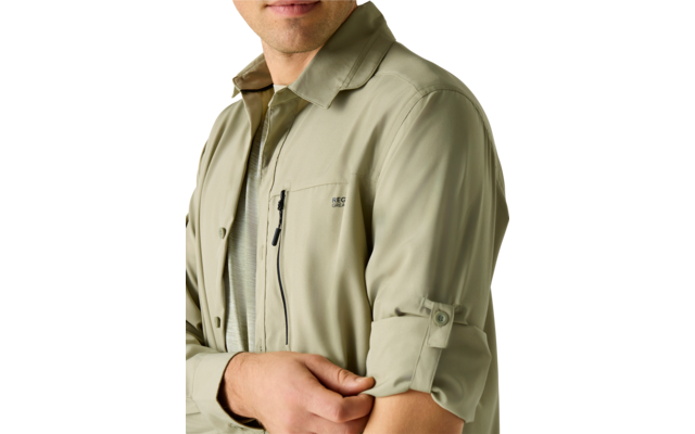 Oberkörper und unteres Gesicht einer Person in hellgrüner Hemdjacke mit Reißverschlusstasche auf der Brust, hochgekrempelter Ärmel mit Riegel, Hand hält den Ärmel; heller einfarbiger Hintergrund