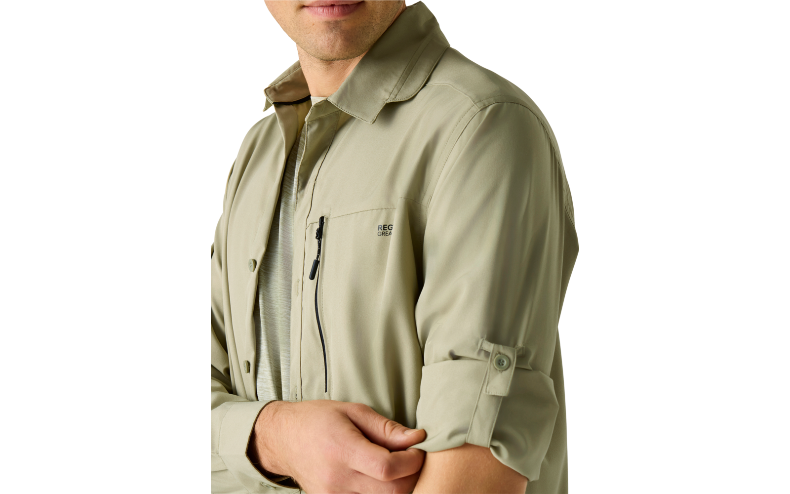 Oberkörper und unteres Gesicht einer Person in hellgrüner Hemdjacke mit Reißverschlusstasche auf der Brust, hochgekrempelter Ärmel mit Riegel, Hand hält den Ärmel; heller einfarbiger Hintergrund