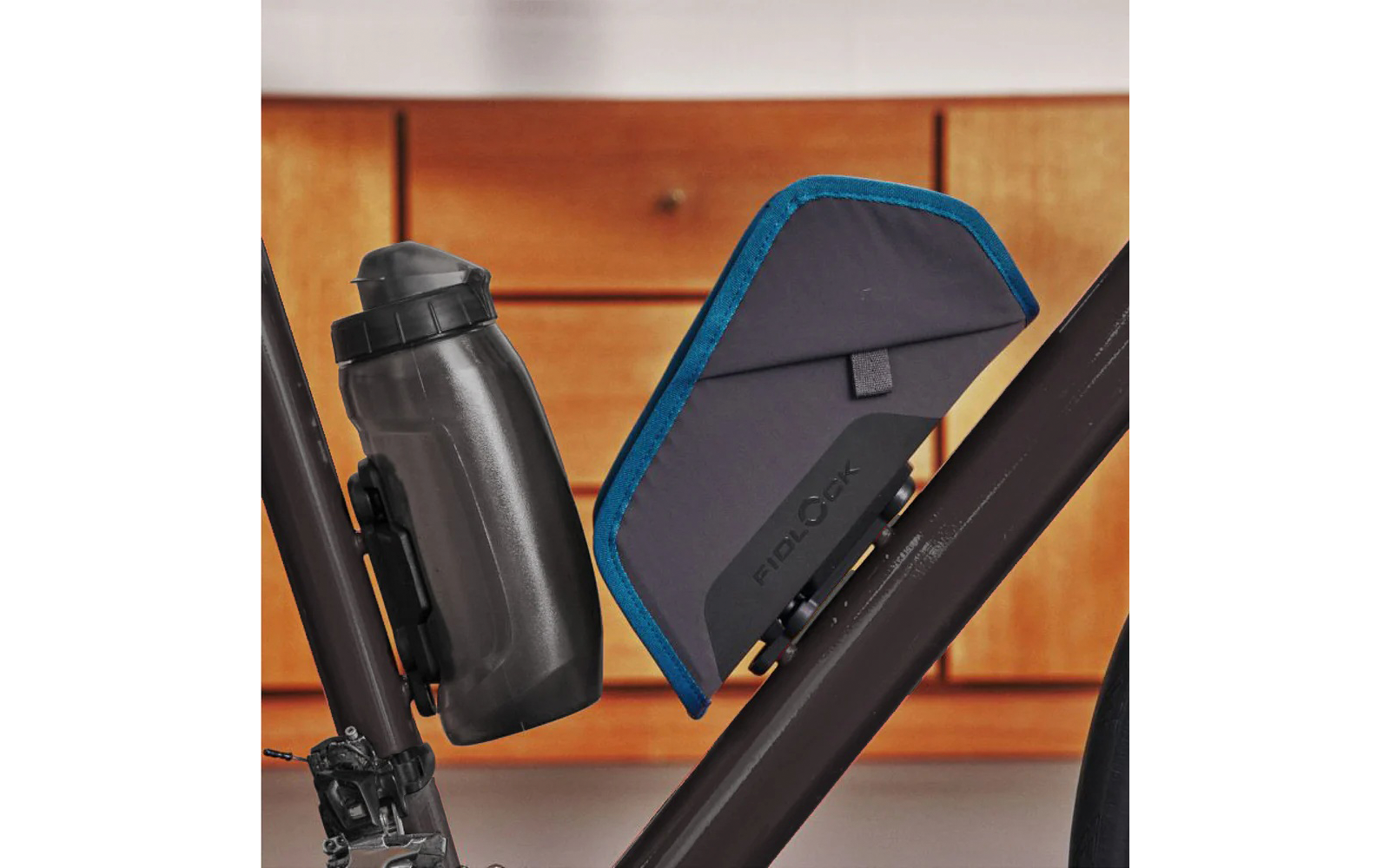 Fahrradrahmen mit schwarzer Trinkflasche und dreieckiger Rahmentasche mit blauem Rand vor Holzschubladen
