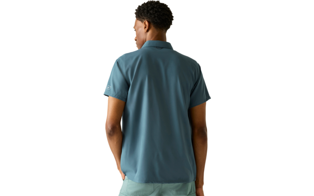 Person von hinten, trägt blaugrünes kurzärmeliges Poloshirt und hellgrüne Shorts vor hellem Hintergrund