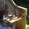 Holzstuhl mit zwei gefüllten Gläsern und einer Flasche auf einem Holztablett