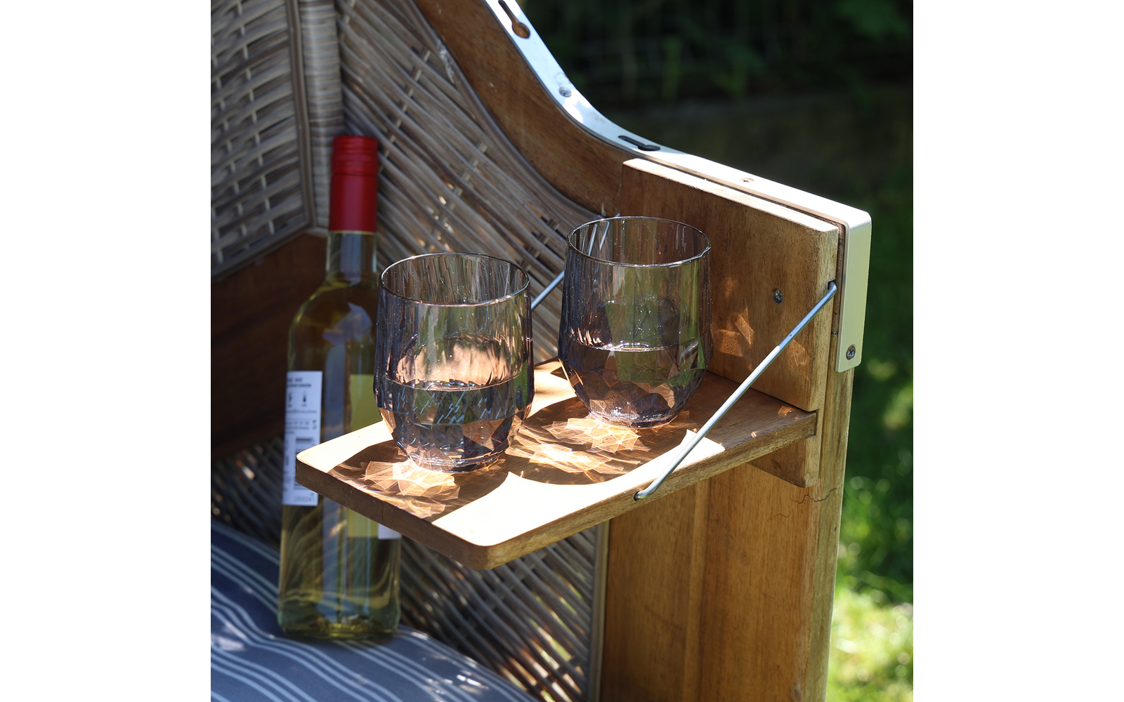 Holzstuhl mit zwei gefüllten Gläsern und einer Flasche auf einem Holztablett