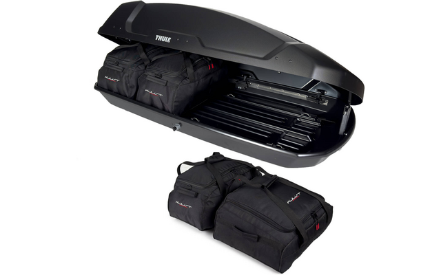 Schwarze offene Dachbox mit "Thule"-Logo, zwei schwarze Taschen im Inneren und zwei schwarze Taschen vor der Box
