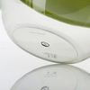 Vue inférieure d'un récipient en verre transparent rond avec un insert vert, une goupille métallique centrale, des marquages en relief et le texte "Made in Germany", reflété sur une surface blanche