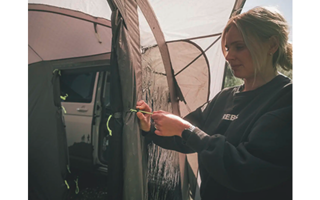 Frau steht neben einem Auto und hält einen Schlüssel in der Hand