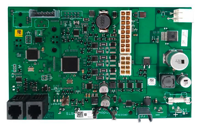 Groene printplaat met veel elektronische onderdelen: twee zwarte rechthoekige connectoren linksonder, meerdere zwarte geïntegreerde schakelingen, een witte meerpolige connector midden-rechts, zilverkleurige cilindrische componenten, ronde spoelen, talrijke kleine SMD-onderdelen en witte opdrukken