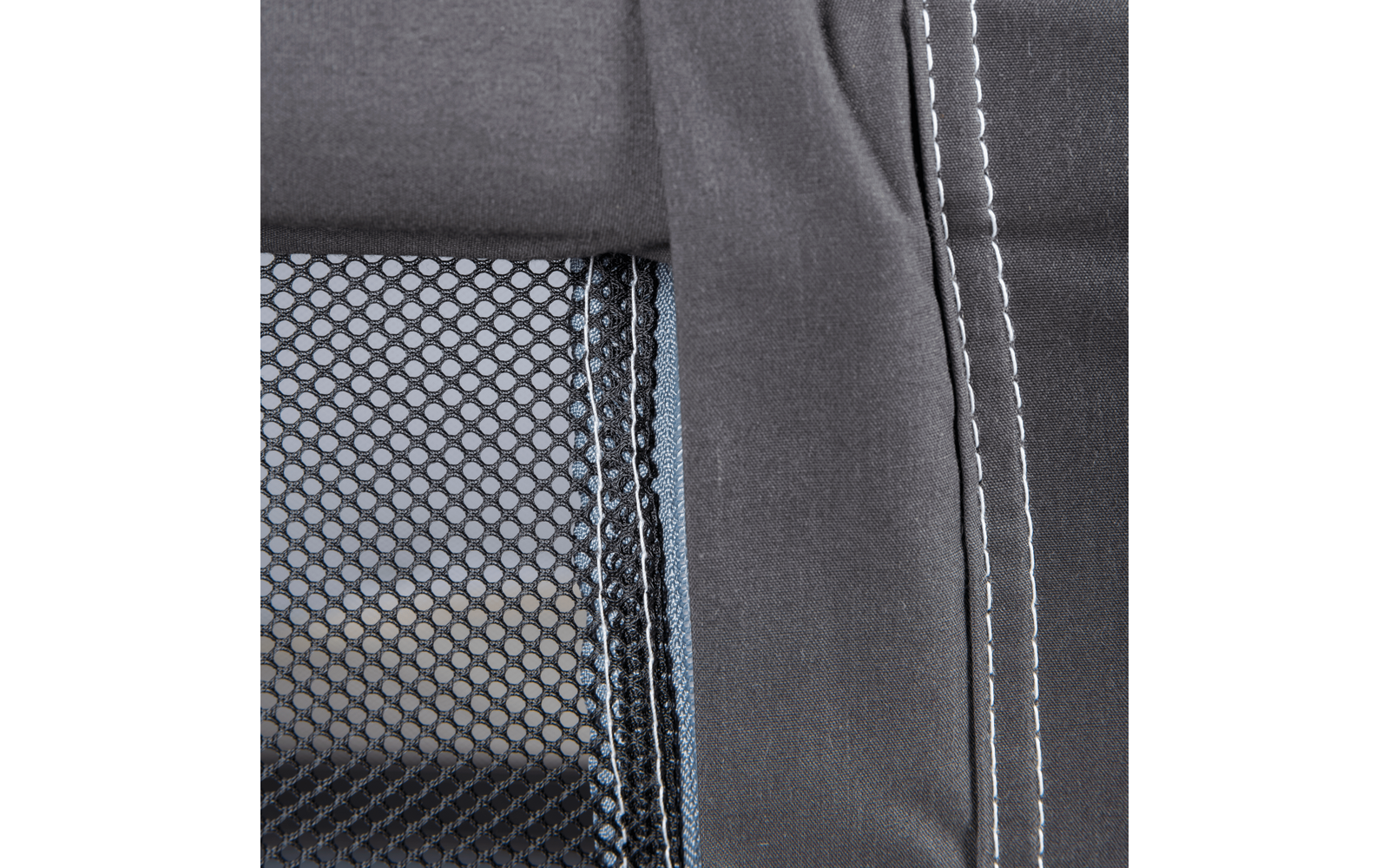 Close-up of dark fabric with white stitching and adjacent dark mesh fabric with a visible seam edge