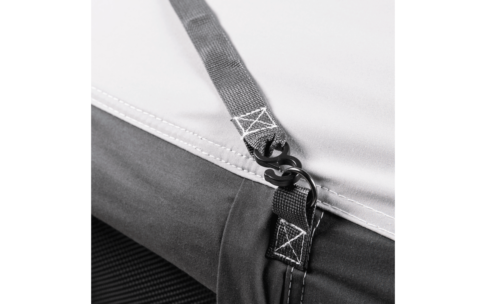 Close-up of fabric with stitched straps, visible seams, and two black hooks hooked into each other