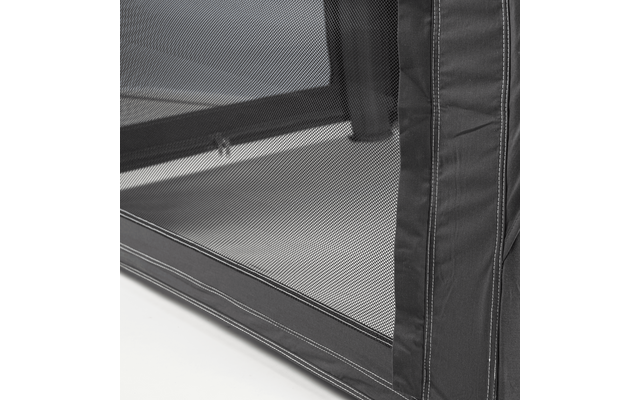 Close-up of black mesh with a fine weave, fabric edge with stitching on the right, horizontal bar visible behind the mesh, light surface underneath