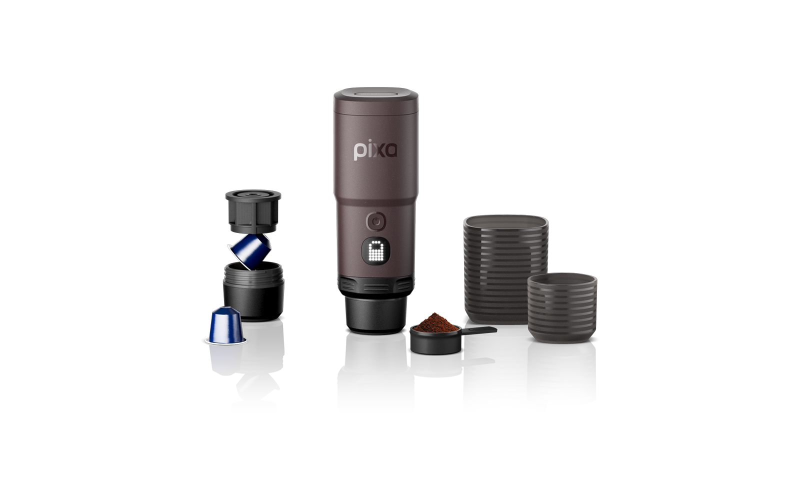 Appareil cylindrique brun portant l'inscription "pixa", à côté deux dosettes, un porte-dosette ouvert, un petit récipient de café moulu et deux récipients ronds empilés