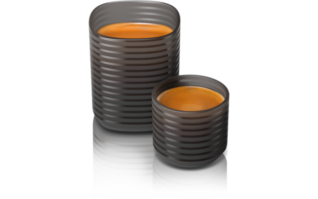 Deux tasses côtelées foncées contenant un liquide orange, une grande à l'arrière et une petite à l'avant sur une surface réfléchissante