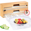 Caja de madera con dos soportes para rollos, film transparente cubriendo un plato blanco con ensalada de frutas, rodajas de manzana a la izquierda