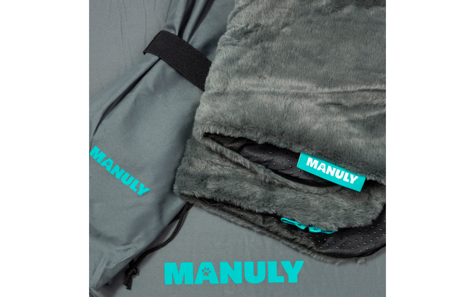Gefalteter grauer Kunstfellstoff mit schwarzem, gepunktetem Innenfutter, türkisfarbenem Reißverschluss und türkisfarbener Rechteck‑Banderole mit Aufdruck "MANULY"; daneben grauer Beutel mit schwarzem Tragegurt und türkisfarbener Aufschrift "MANULY"; 