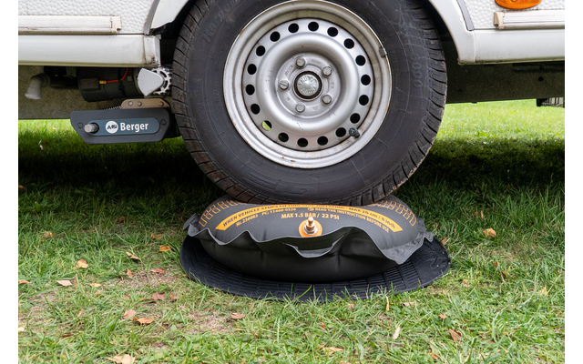 Rad eines weißen Fahrzeugs auf einem schwarz-gelben aufblasbaren Kissen auf Gras
