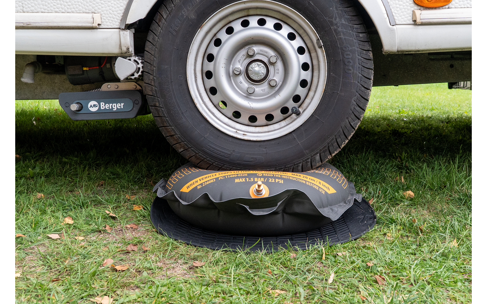 Rad eines weißen Fahrzeugs auf einem schwarz-gelben aufblasbaren Kissen auf Gras
