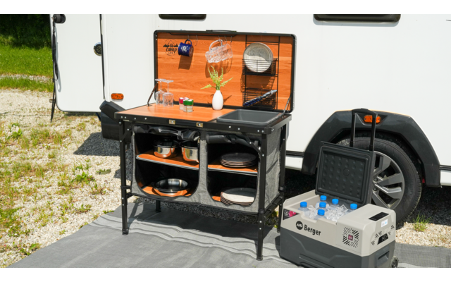Buitenkookplaats met open kast voor een camper, draagbare stroomgenerator ernaast op de grond