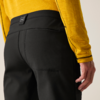 Achteraanzicht van taille tot dij: zwarte broek met stiknaad en klein label in de tailleband, geel langarmshirt, rechterhand langs het lichaam