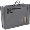Grijze rechthoekige tas met handvatten, opdruk 'OUTDOOR CARPET NAVA 2 X 3 M' en rond venster met opgerold gestreept vloerkleed