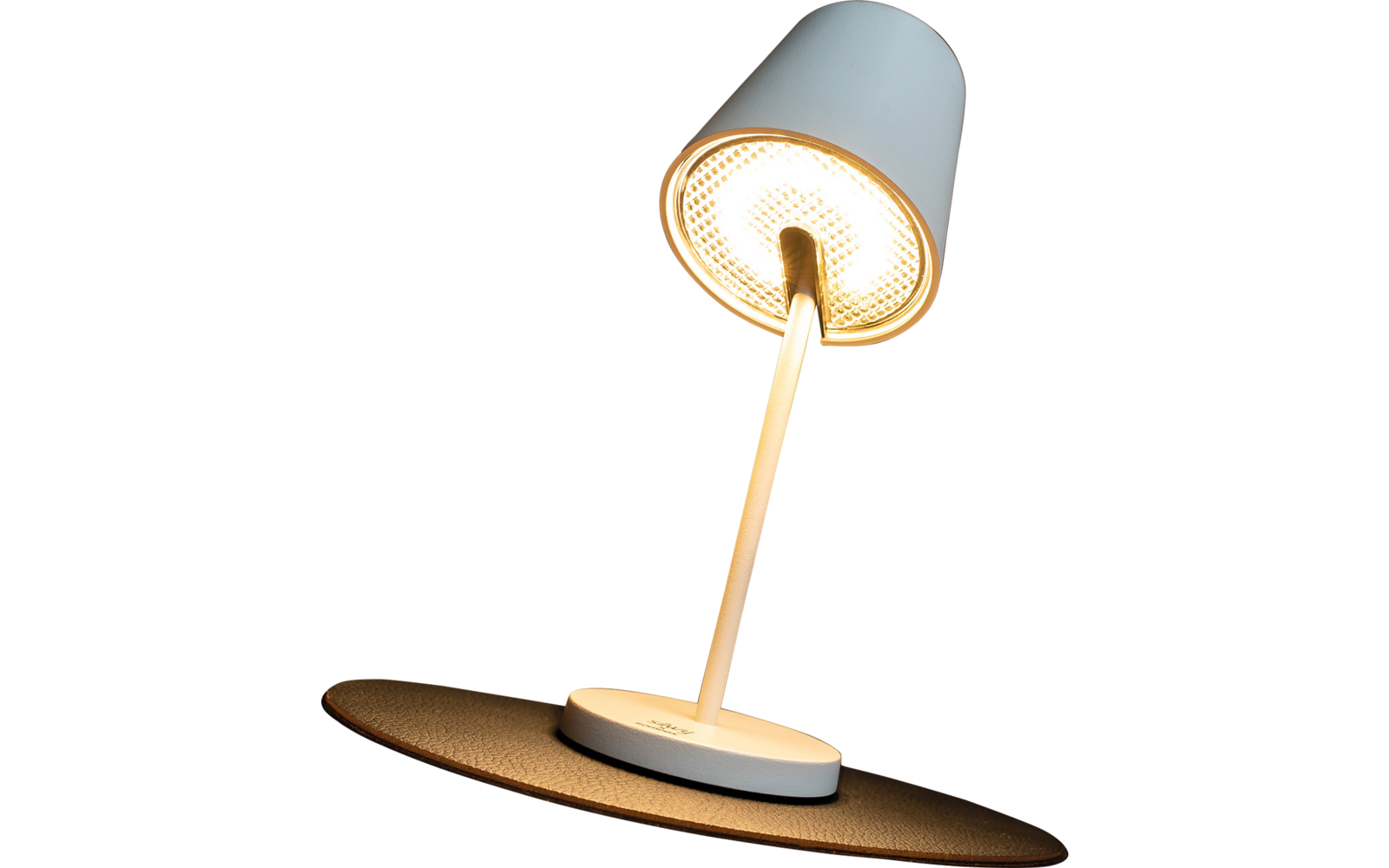 Lampe de bureau blanche avec abat-jour orienté vers le bas, allumée, posée sur un tapis rond noir sur une surface en bois ; en arrière-plan un vase avec des fleurs séchées devant des lattes de bois verticales