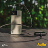 Een zilveren powerbank met een kabel op een houten tafel, een smartphone ernaast