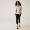 Femme aux cheveux bouclés portant une veste claire, un legging noir et des chaussures claires marchant sur un fond clair