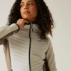 Femme aux cheveux bouclés portant une veste matelassée gris clair regardant vers le haut sur le côté