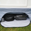 Offenes Fach mit weißer Innenfläche und grauem Stoffrand; darin runde schwarze Tasche mit Aufschrift 'Dometic Safari Chef 30', durchsichtige Reißverschlusstasche mit dunklem rechteckigem Gegenstand und kleiner Metallzylinder; Gras vor dem Fach