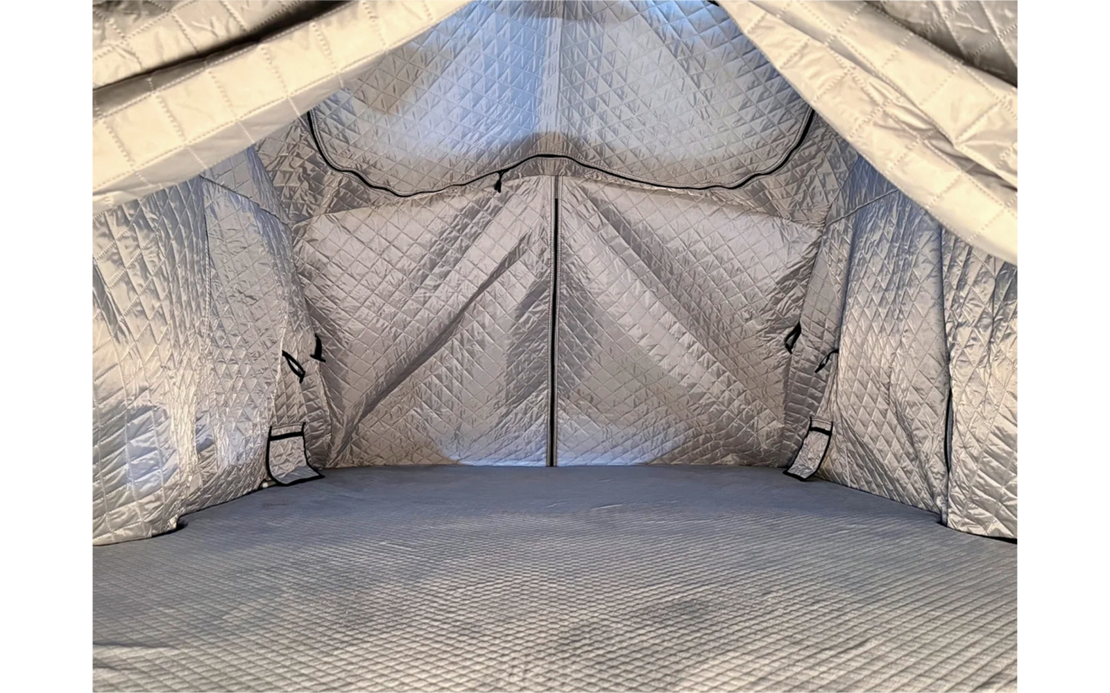 Binnenkant van een tent met gestikte zilvergrijze isolatie, puntdak, centrale rits en gestikte vloer