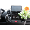Blick auf die Mittelkonsole eines Autos mit einem Bildschirm, Klimabedienelementen und einem kleinen Blumenstrauß