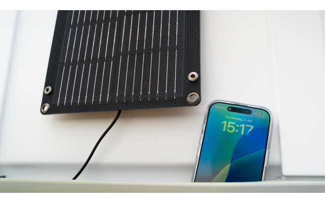 Panneau solaire au mur à côté d'un smartphone affichant l'état de charge