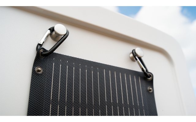 Panneau solaire noir avec fixations blanches sur une surface blanche