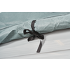 Close-up of a light green fabric with a fine dotted pattern and a black fabric bow on a white surface