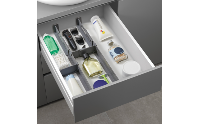 Geöffnete Schublade mit Zahnpflegeartikeln, darunter eine Zahnbürste, Zahncreme, Zahnseide, Mundspülung und Rasierer