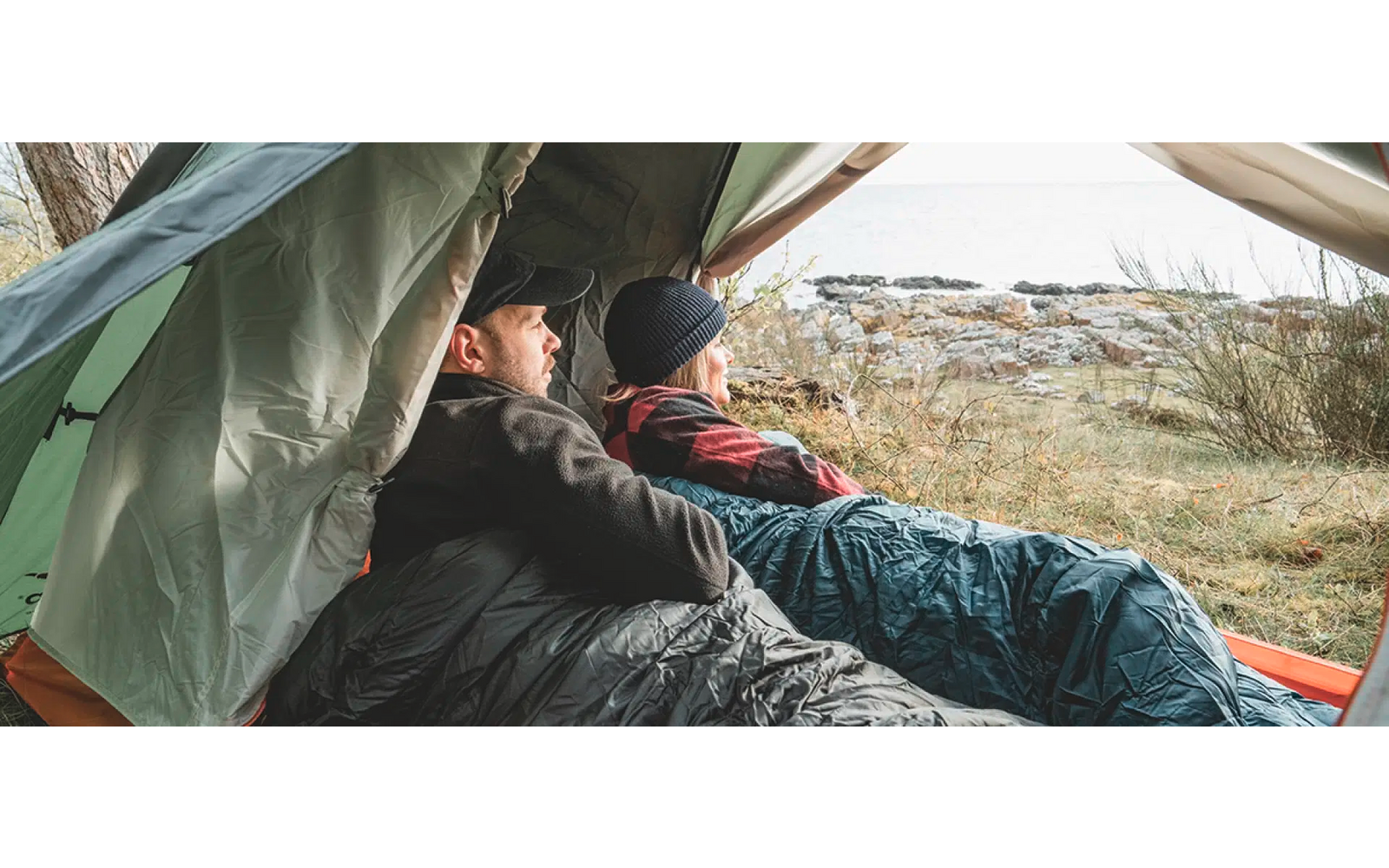 Person sitzt auf dem Boden und lehnt sich an eine grüne Plane