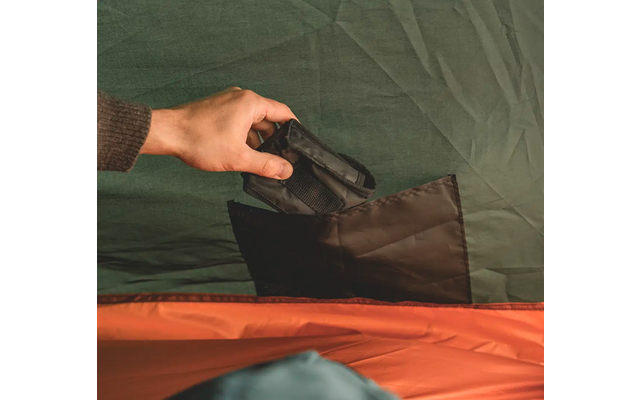 Hand, die einen schwarzen Gegenstand in eine Tasche steckt