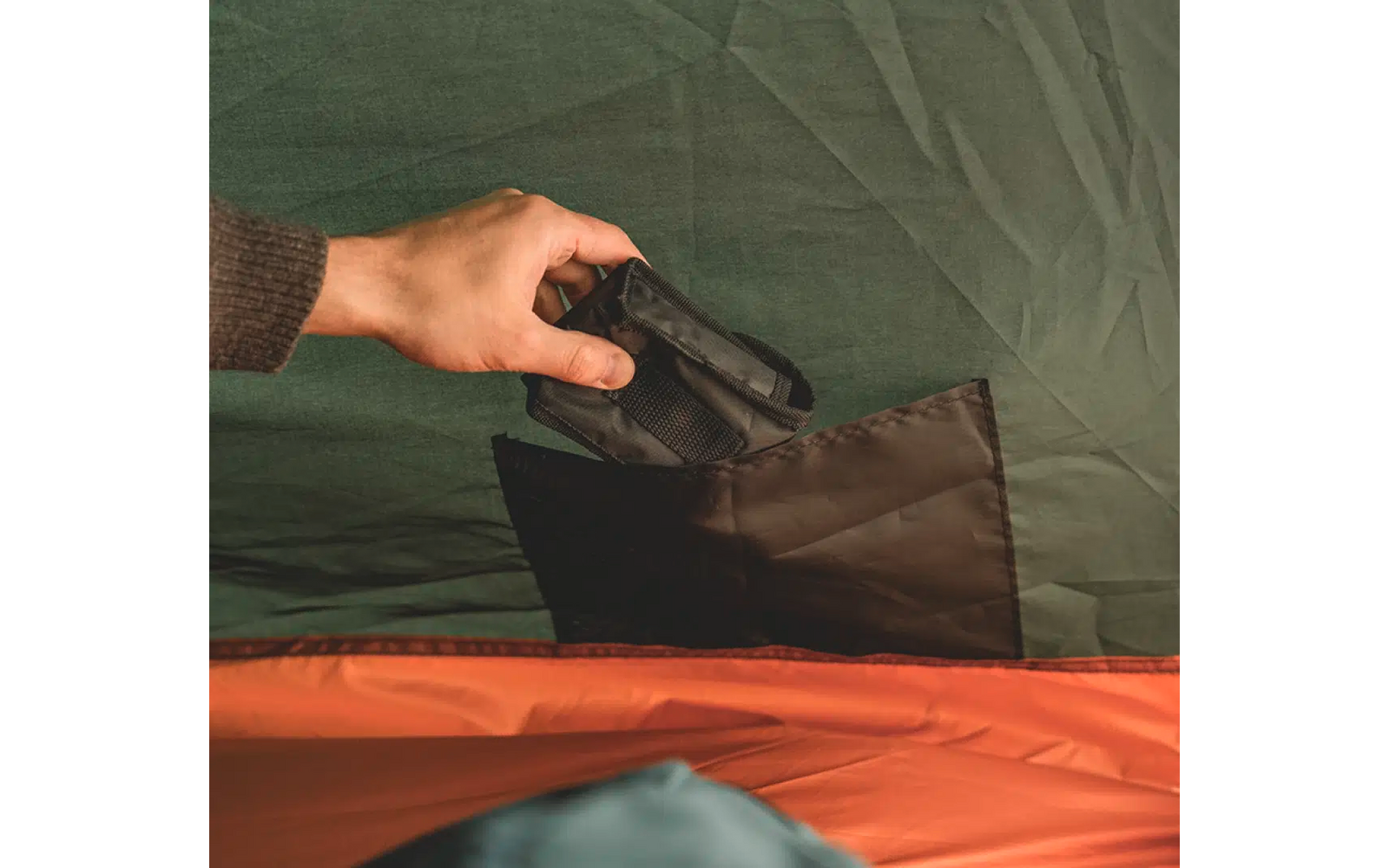 Hand, die einen schwarzen Gegenstand in eine Tasche steckt