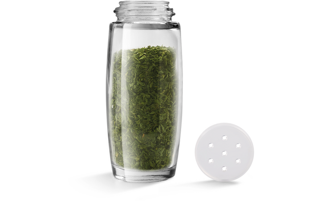 Transparante kruidenpot met groen gedroogd kruid, deksel naast de pot